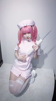 a woman with pink hair is sitting on a table and holding a knife in her hand