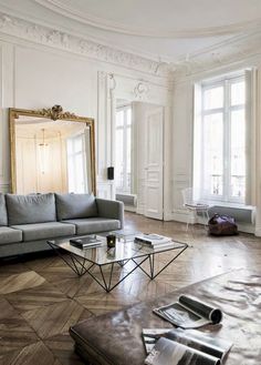 a living room filled with lots of furniture and large mirrors on the wall above it