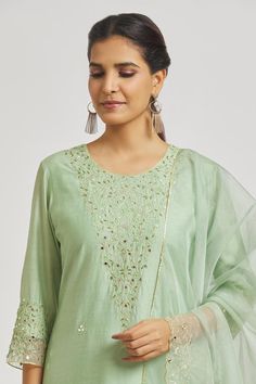 Mint green A-line kurta with floral vine and mirror work embroidery. Comes with embroidered hem pant and dupatta.
Components: 3
Pattern: Embroidered
Type Of Work: Floral Vine
Neckline: Round
Sleeve Type: Three Quarter
Fabric: Organza, Muslin, Chanderi
Color: Green
Other Details: 
Attached lining
Back elasticated pant waistband
Length:
Kurta: 48
Pant: 37
Approx. product weight: 1 kg
Occasion: Puja - Aza Fashions Spring Chanderi Salwar Kameez With Mirror Work, Spring Chanderi Palazzo Set With Mirror Work, Spring Chanderi Anarkali Set With Mirror Work, Green Straight Kurta Set With Mirror Work, Green Chanderi Palazzo Set With Floral Embroidery, Spring Green Sharara With Zari Work, Green Sharara With Zari Work For Spring, Spring Chanderi Dupatta With Mirror Work, Pista Green Chanderi Palazzo Set With Mirror Work