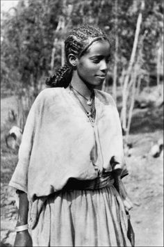 an old black and white photo of a young woman in native garb with birds around her neck