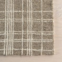 a close up view of a rug on a wooden floor with white and gray stripes