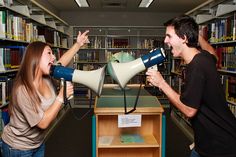 a woman yelling into a man's megaphone in a library