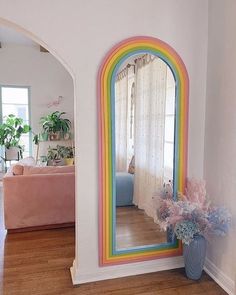 there is a large mirror on the wall next to a vase with flowers in it