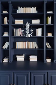 a bookshelf filled with lots of books next to a vase on top of a table