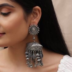 Give your ethnic look a perfect finish with Vastrabhushan's tribal banjara antique earrings. These unique boho earrings are handmade with love and expertise, just for you. These minimal oxidized silver earrings with quintessential cute little silver chimes are a beautiful ornate masterpiece engraved with extraordinary detailing that will do justice to your outfit and make you shine anywhere you go. You can preferably wear these to weddings, birthday parties, or any other occasion. Also, these In Antique Jhumka, Oxidised Jewelry, Oxidized Jewellery, Oxidized Silver Earrings, Earrings Big, Jewellery Gifts, Black Polish, Indian Earrings, Jhumka Earrings