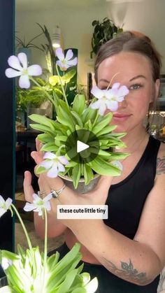 a woman holding a potted plant with white flowers in it's hands and the caption reads, those cute little tiny