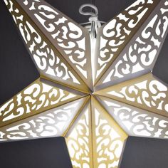 a white star hanging from the ceiling with intricate designs on it's sides and bottom