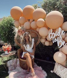 a woman sitting in a wicker chair under an arch made out of balloons that read bride to be