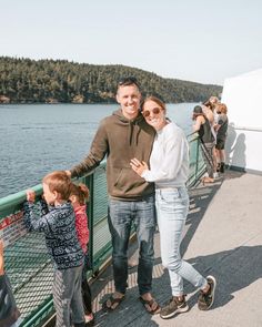 a man, woman and child standing on a bridge over water with trees in the background