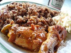 a plate full of food with rice and meat on it, next to a bottle of beer