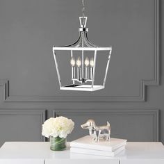 a chandelier hanging from the ceiling over a table with flowers and books on it