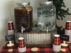 mason jars are lined up on top of a table with red and black striped paper cups