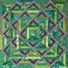 a green and black quilt with an intricate design on the center, surrounded by polka dots