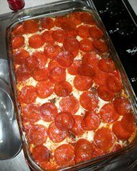 pepperoni and cheese pizza in a baking dish on the stove top next to a measuring spoon