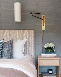 a bed room with a neatly made bed and a lamp on the wall next to it