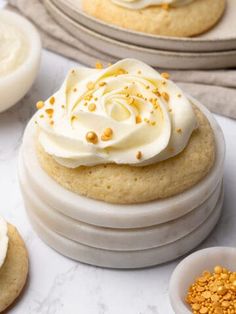 two cookies with white frosting and sprinkles on top, next to other dessert items