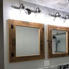 a bathroom with three mirrors and lights on the wall above the sinks in front of them