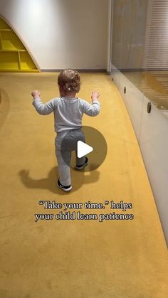 a small child is walking on the floor in front of a wall with a quote