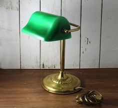 a green desk lamp sitting on top of a wooden table next to a pair of scissors