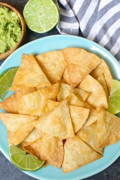 tortilla chips on a plate with guacamole and limes