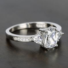 a three stone diamond ring with side stones on the band and an oval cut diamond in the center