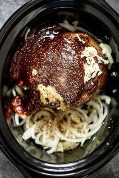 an overhead view of some food in a crock pot with onions and seasoning