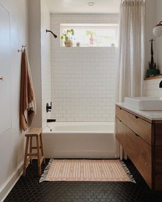 a bathroom with black and white flooring and a bathtub next to a window