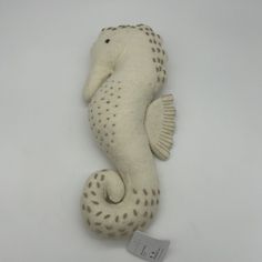 a stuffed sea horse is shown on a white background with a tag attached to it