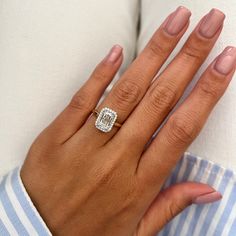 a woman's hand with a diamond ring on her left hand, wearing a blue and white striped shirt