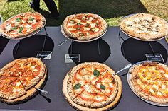 several different types of pizza on display at an outdoor event