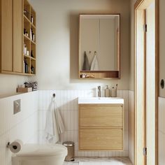 a white toilet sitting next to a bathroom sink under a wooden mirror mounted on a wall