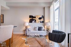 a living room filled with furniture and a painting on the wall above it's windows