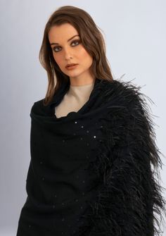 This black scarf is woven from the finest premium cashmere. It features a smattering of tonal black sequin across the scarf with the delicate application of black ostrich feathers at the long ends. Meticulously hand crafted, this scarf is the perfect fusion of opulence, glamour and sophistication. The application of ostrich feathers add a touch of extravagance whilst the scattered sequin introduces a subtle sparkle. Whether draped casually for everyday chic or worn on special occasions, this stu Elegant Evening Shawl With Sequins, Luxury Black Scarf For Fall, Luxury Black Winter Scarves, Winter Evening Shawl Scarf, Black Winter Evening Shawl, Black Evening Shawl For Winter, Elegant Fringed Shawl For Winter, Elegant Winter Shawl With Fringe, Black Cashmere Scarf