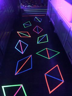 the floor is lit up with neon lights and shapes on it, as well as black light