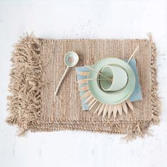 a place mat with a tea cup, saucer and spoons on top of it