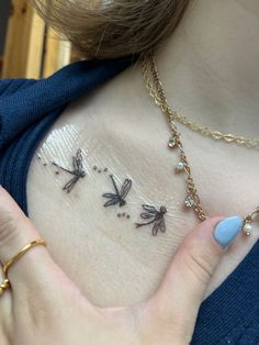 a woman holding her chest with three dragonflies tattoo on it's left side