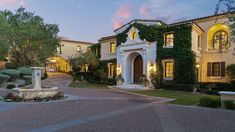 a large house with lots of windows and plants on the front lawn at night time