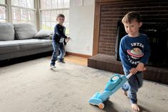 two young boys are playing in the living room with their toy vacuum mop and toys