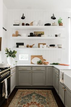 a kitchen with gray cabinets and white walls, an area rug in front of the stove