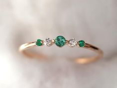 an emerald and diamond three stone ring on a white background with the top half in yellow gold