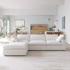 a large white couch sitting in a living room next to a kitchen and dining area