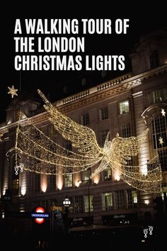 the london christmas lights are lit up in front of a large building with an angel on it