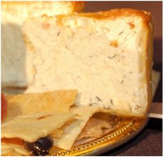 a piece of bread with cheese and fruit on it sitting on a plate next to some crackers