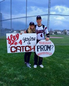 two people standing in the grass holding up signs that say you're a catch prom