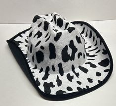 a white and black animal print hat on top of a table next to a cell phone