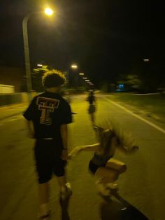 two young boys are skateboarding down the street at night time while another boy is jumping on his skateboard