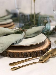 the table is set with silverware, napkins and gold utensils on wood slices