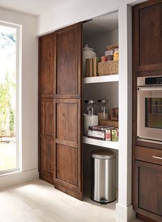 a kitchen with wooden cabinets and stainless steel trash can in the corner next to it