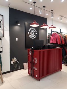 a clothing store with clothes on racks and lights hanging from the ceiling above it's counter