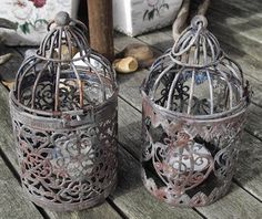 two metal bird cages sitting on top of a wooden table